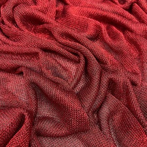 Könnte beinhalten: Rotes Netzgewebe mit einem strukturierten, gewebten Muster. Der Stoff ist drapiert und gefaltet und erzeugt einen weichen, fließenden Look.