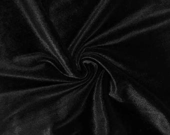 May include: Close-up of a black velvet fabric with a soft, luxurious texture. The fabric is draped and swirled, creating shadows and highlights that emphasize its depth and sheen. The image showcases the rich, dark color and the fabric's smooth surface.