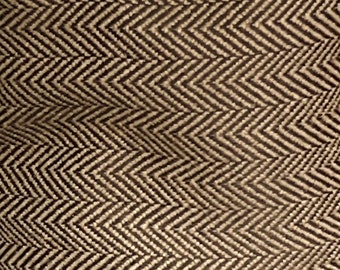 Può includere: Un primo piano di un tessuto marrone e bianco con un motivo a spina di pesce. Il tessuto ha una texture sottile e un aspetto leggermente ondulato.
