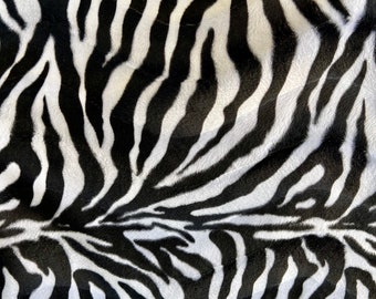 May include: Black and white zebra print fabric with a soft, fuzzy texture.
