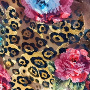 May include: A brown fabric with a leopard print pattern and a floral design. The flowers are red, pink, and blue.