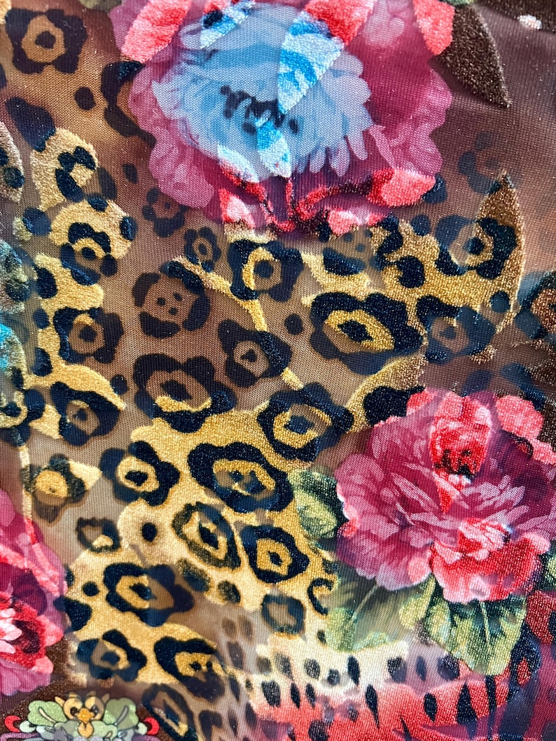May include: A brown fabric with a leopard print pattern and a floral design. The flowers are red, pink, and blue.