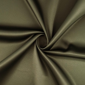 Pode incluir: Tecido de cetim verde oliva com um brilho sutil. O tecido é drapeado e dobrado, criando sombras e destaques. O material tem uma textura suave e uma aparência luxuosa, adequado para vestuário ou decoração de casa.