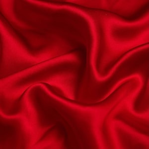May include: A close-up of a smooth, red satin fabric with soft, flowing folds.