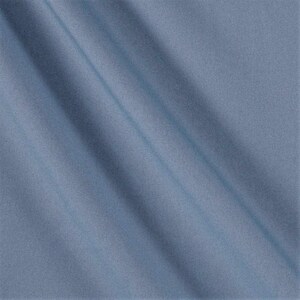 May include: A close-up shot of a light blue fabric with diagonal folds. The fabric has a smooth texture and a subtle sheen, creating a soft, flowing appearance. The color is a muted, dusty blue.
