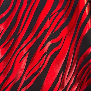 Puede incluir: Tela metálica roja y negra con estampado de cebra.