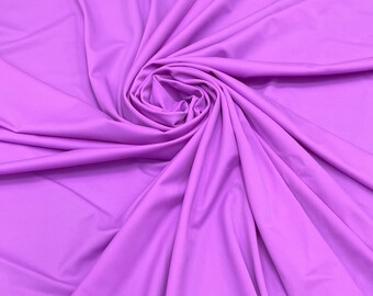 May include: A close-up of a smooth, soft, lilac fabric. The fabric is draped and folded, creating a swirling pattern.
