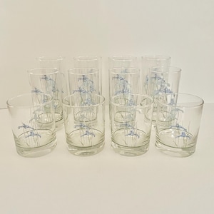 Puede incluir: Un conjunto de doce vasos transparentes, cada uno adornado con un delicado diseño floral azul. Los vasos están dispuestos sobre una superficie blanca, resaltando su diseño sencillo. Ideales para servir bebidas.