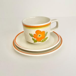 May include: A white ceramic mug with a black handle and the text "But First, Coffee" in a bold, black font. The mug is set against a blurred background, highlighting its clean design.