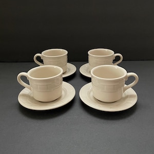 Puede incluir: Juego de cuatro tazas de té y platillos de cerámica blanca con un patrón de tejido de cesta.