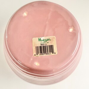May include: The bottom of a pink ceramic vase with white stripes. The vase has a green label with the text "Haeger" and "Copyright 1998" and the number "953-11". A barcode is also on the label.
