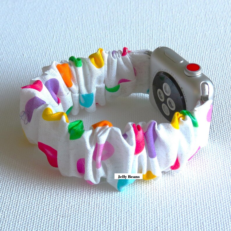 May include: White Apple Watch band with a colorful jelly bean pattern. The band is made of fabric and has a stretchy, comfortable fit. The text "Jelly Beans" is printed on the band.