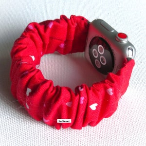 May include: Red Apple Watch band with a white heart pattern. The band is made of a stretchy fabric and has a 'So Sweet' label.
