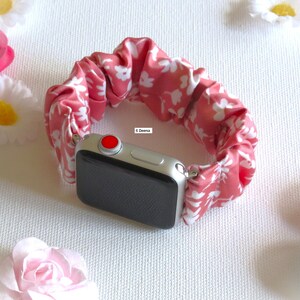 May include: A pink and white floral patterned watch band made of fabric. The band is attached to a silver Apple Watch.