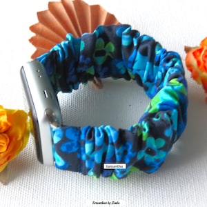 May include: A blue and green floral patterned watch band with the text "Samantha" and "Scrunchies by Linda" on it.