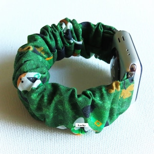 Peut inclure: Bracelet de montre en tissu vert et blanc avec un tr&egrave;fle et un imprim&eacute; d'animaux de dessin anim&eacute;. Le bracelet est fait d'un mat&eacute;riau extensible et est con&ccedil;u pour s'adapter &agrave; une montre intelligente. Le texte "Lucky" est imprim&eacute; sur le bracelet.