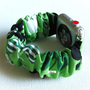 Peut inclure: Un bracelet de montre Apple en tissu &agrave; motif vert, noir et blanc avec le mot "Clover" imprim&eacute; dessus.
