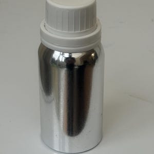 May include: A silver metal bottle with a white screw-on lid. The bottle is cylindrical and has a smooth, shiny surface.