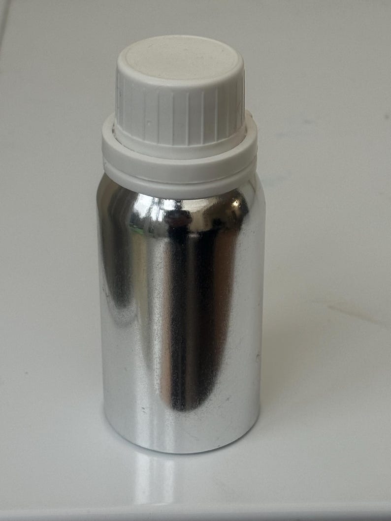May include: A silver metal bottle with a white screw-on lid. The bottle is cylindrical and has a smooth, shiny surface.