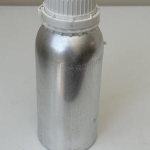 Pode incluir: Uma garrafa de metal prateado com uma tampa de rosca de pl&aacute;stico branco. A garrafa tem formato cil&iacute;ndrico e uma tampa texturizada. A garrafa &eacute; provavelmente usada para armazenar l&iacute;quidos ou outras subst&acirc;ncias. A garrafa est&aacute; limpa e parece nova.
