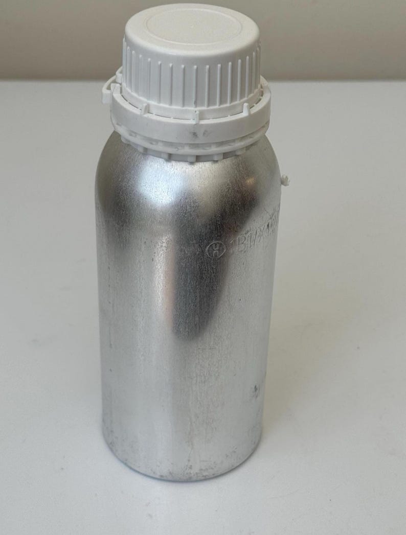Pode incluir: Uma garrafa de metal prateado com uma tampa de rosca de pl&aacute;stico branco. A garrafa tem formato cil&iacute;ndrico e uma tampa texturizada. A garrafa &eacute; provavelmente usada para armazenar l&iacute;quidos ou outras subst&acirc;ncias. A garrafa est&aacute; limpa e parece nova.