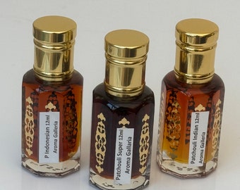 May include: Three hexagonal glass perfume bottles with gold-colored caps, each containing amber-colored liquid. The bottles feature gold decorative patterns and white labels reading P Indonesian 12ml, Patchouli Super 12ml, and Patchouli Indian 12ml.