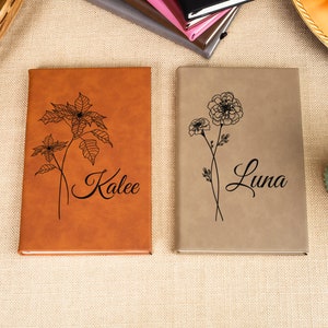 May include: Two brown leather journals with floral designs and personalized names, "Kalee" and "Luna", on the covers.
