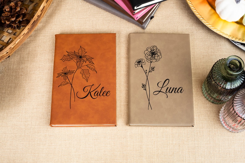 May include: Two brown leather journals with floral designs and personalized names, "Kalee" and "Luna", on the covers.
