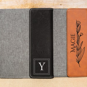 May include: A set of three personalized leatherette journals with a gray, black, and brown cover. The covers are embossed with a floral design and the name "MAGGIE" and the initial "Y".