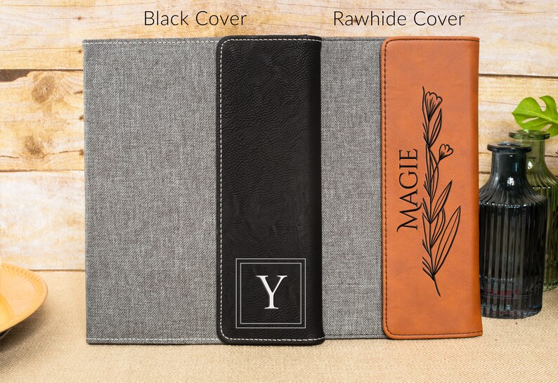 May include: Two personalized notebook covers, one with a black cover and the initial "Y" and the other with a brown leather cover with the name "MAGGIE" and a floral design.