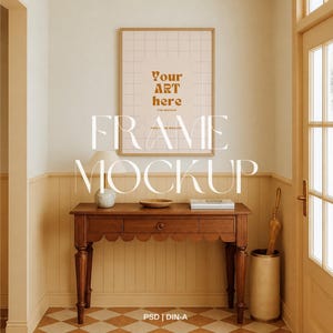 May include: A rectangular wooden picture frame hanging on a wall above a wooden console table. The frame contains a grid pattern and the text "Your ART here". The console table features a scalloped edge, a drawer, and a small lamp on top.