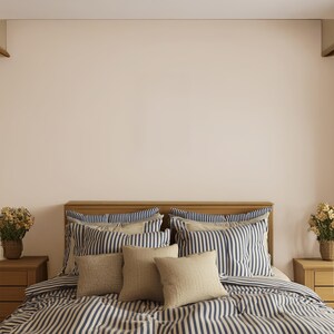 May include: A bed with a wooden headboard and matching nightstands. The bedding features a blue and white striped pattern, with several pillows in matching stripes and solid beige. Two small flower arrangements sit on the nightstands.