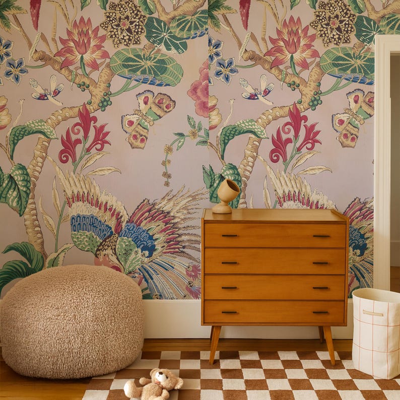 May include: A room scene featuring a wooden dresser with four drawers, a plush round ottoman, and a checkered rug. The wall is adorned with a colorful floral and butterfly wallpaper. A teddy bear and a woven basket complete the decor.