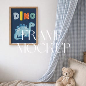 Op de afbeelding: Een ingelijste print met een blauwe dinosaurusillustratie en het woord "DINO" in kleurrijke letters. Het kunstwerk zit in een houten lijst en hangt aan een witte muur. Een teddybeer en een blauw-wit geruit gordijn zijn op de achtergrond.