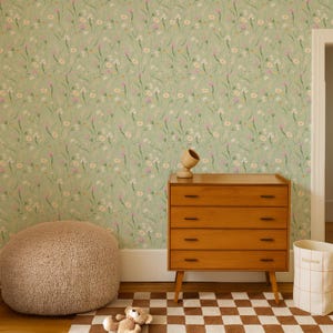 May include: A room with light green floral wallpaper, a wooden dresser, and a brown and white checkered rug. A tan beanbag chair and a teddy bear are on the floor. A wooden decorative object sits on the dresser.