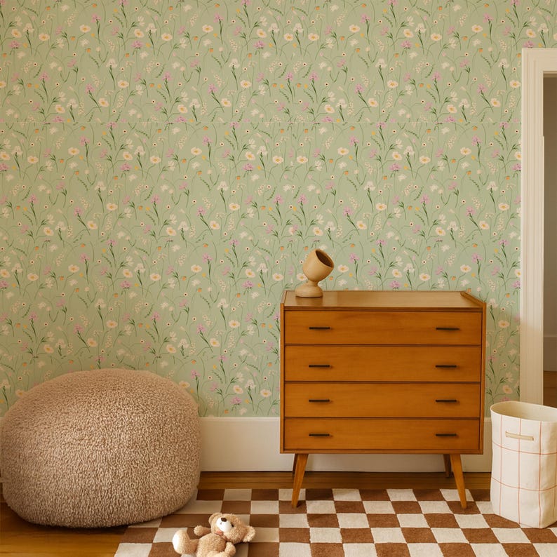 May include: A room with light green floral wallpaper, a wooden dresser, and a brown and white checkered rug. A tan beanbag chair and a teddy bear are on the floor. A wooden decorative object sits on the dresser.