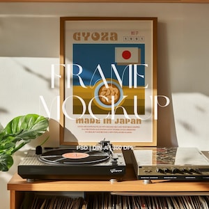 May include: A framed poster with a retro design featuring the Japanese word "gyoza" and a red circle with a white star. The poster is on a shelf above a turntable and vinyl records.