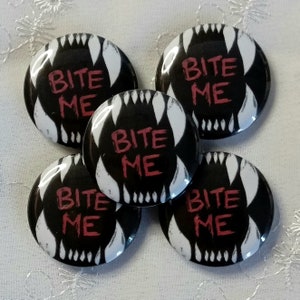May include: Five black and white button badges with the text "Bite Me" in red. The badges feature a graphic of a set of teeth.