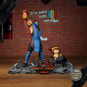 Könnte beinhalten: Detaillierte Mortal Kombat-Statue mit Sub-Zero, der einen abgetrennten Kopf und eine Wirbelsäule hält. Die Statue hat ein schwarz-blaues Farbschema, mit dem Mortal Kombat-Logo und dem Text "Spine Rip" auf dem Sockel. Der Hintergrund enthält den Text "Diorama Hobi Sanat Atölyesi".