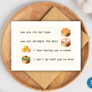 May include: A white card with text and illustrations of dim sum, including siu mai and shrimp dumplings, on a wooden plate with a brown envelope. The text reads: "you are siu mai type, you are shrimply the best, i love having you a-round, i can't be-leaf you're mine."