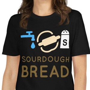 Puede incluir: Camiseta negra con un gráfico blanco de un grifo de agua, un rodillo y un salero con el texto "SOURDOUGH BREAD" en marrón.