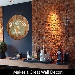 May include: A wooden round sign with a green shamrock and the words "GUINNESS ESTD. 1759" in a brown brick wall setting. Makes a Great Wall Decor!