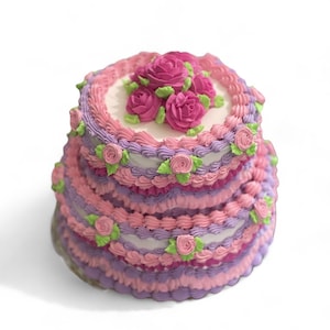 Puede incluir: Un pastel de dos pisos decorado con glaseado rosa y morado y rosas rosas.