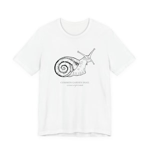 Black short sleeve tee shirt with a hand drawn white image of a garden snail with a detailed spiral shell and underneath the words common garden snail with the latin name beneath that.