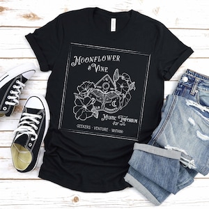 Pode incluir: Camiseta preta com um design gr&aacute;fico branco de uma flor de lua e uma videira com um tabuleiro Ouija e o texto "Moonflower & Vine Mystic Emporium est 1890 - Seekers Venture Within - "