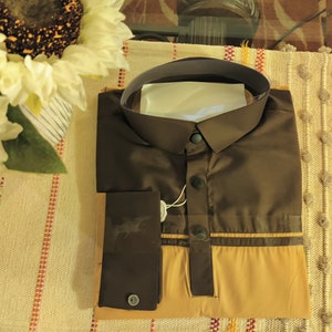 May include: A brown and tan long-sleeved shirt with a white collar and a button-up front. The shirt has a brown trim around the bottom and sleeves.