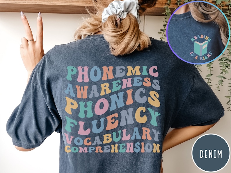 May include: A dark blue t-shirt with the words "PHONEMIC AWARENESS PHONICS FLUENCY VOCABULARY COMPREHENSION" in rainbow colors on the back. The front of the shirt has a small graphic of a book with the text "READING IS A RIGHT".
