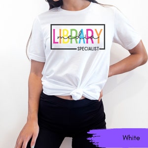 May include: White t-shirt with the text "LIBRARY MEDIA SPECIALIST" in a rainbow color scheme.
