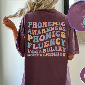 May include: A maroon t-shirt with the words "phonemic awareness, phonics, fluency, vocabulary, comprehension" in rainbow colors on the back. The front of the shirt has a small graphic of a book with the text "Reading is a right".