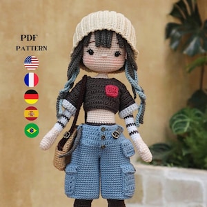 Könnte beinhalten: Eine gehäkelte Puppe mit blauen Haaren, die eine beige Mütze, ein schwarz-weiß gestreiftes Shirt, blaue Jeans-Shorts und rot-graue Schuhe trägt. Die Puppe hält eine braune Tasche. Der Text "PDF PATTERN" und Flaggen der Vereinigten Staaten, Frankreichs, Deutschlands, Spaniens und Brasiliens sind im Hintergrund sichtbar. Der Text "@moonlightcrochet89" ist in der rechten unteren Ecke sichtbar.